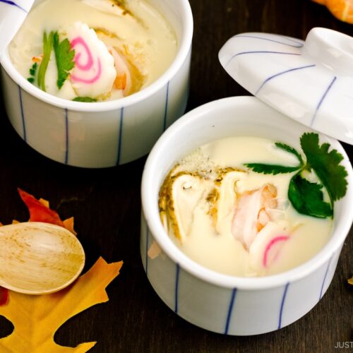 Chawanmushi cups containing matsutake mushrooms, shrimp, and fish cake slices in a savory steamed egg mixture.