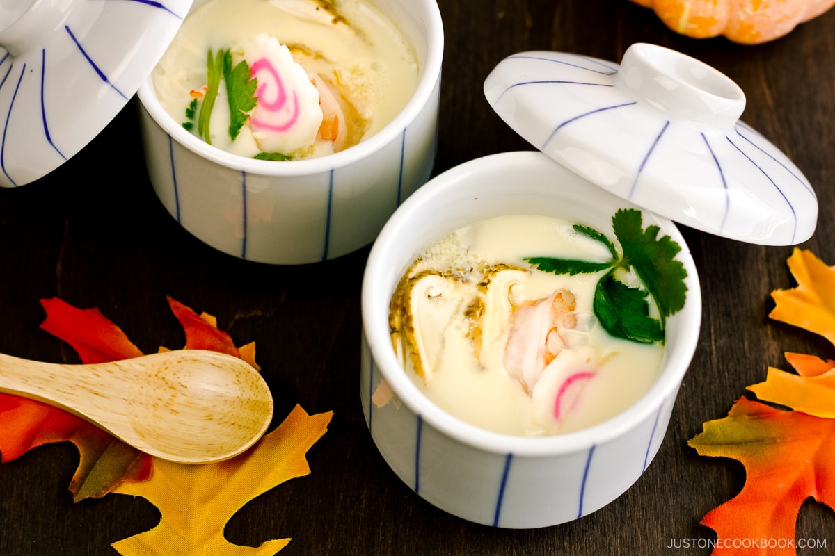 Chawanmushi cups containing matsutake mushrooms, shrimp, and fish cake slices in a savory steamed egg mixture.