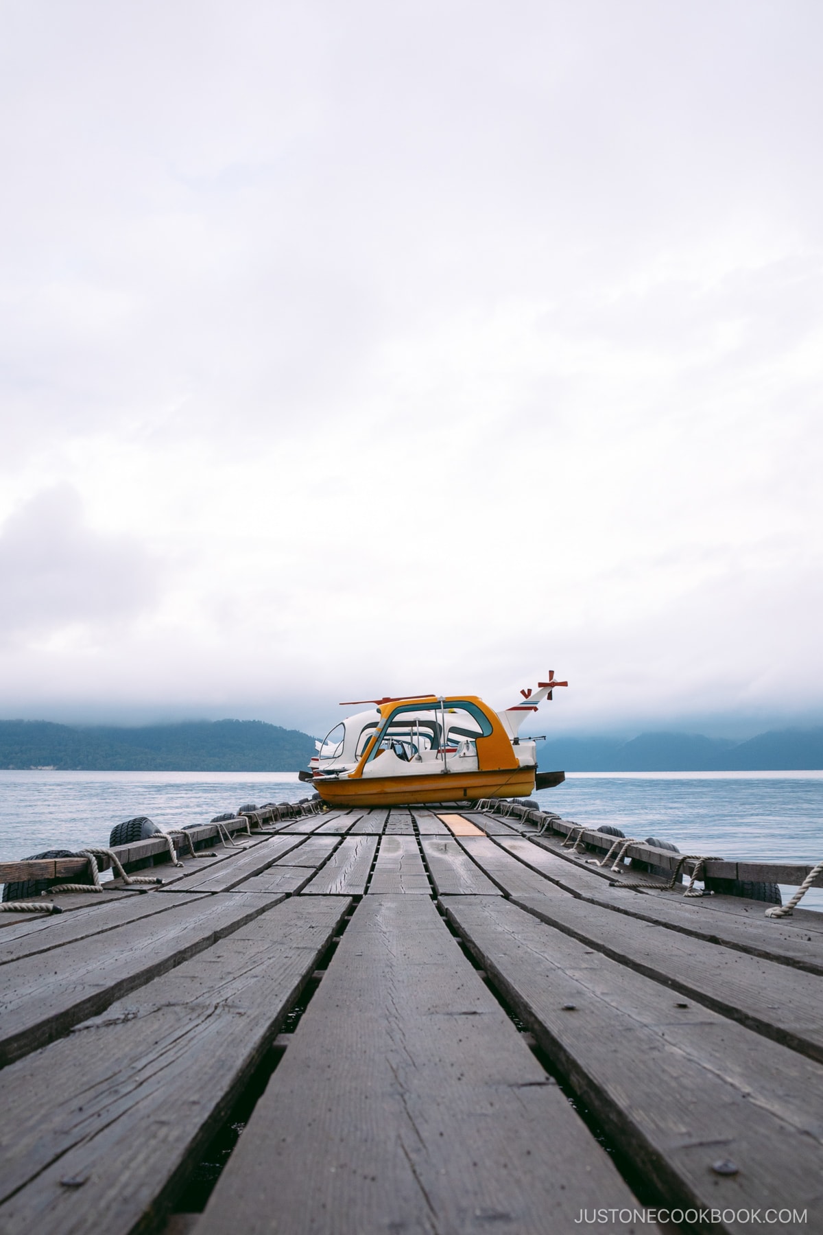 Wooden pier with swan boats at the end at lake Kussharo