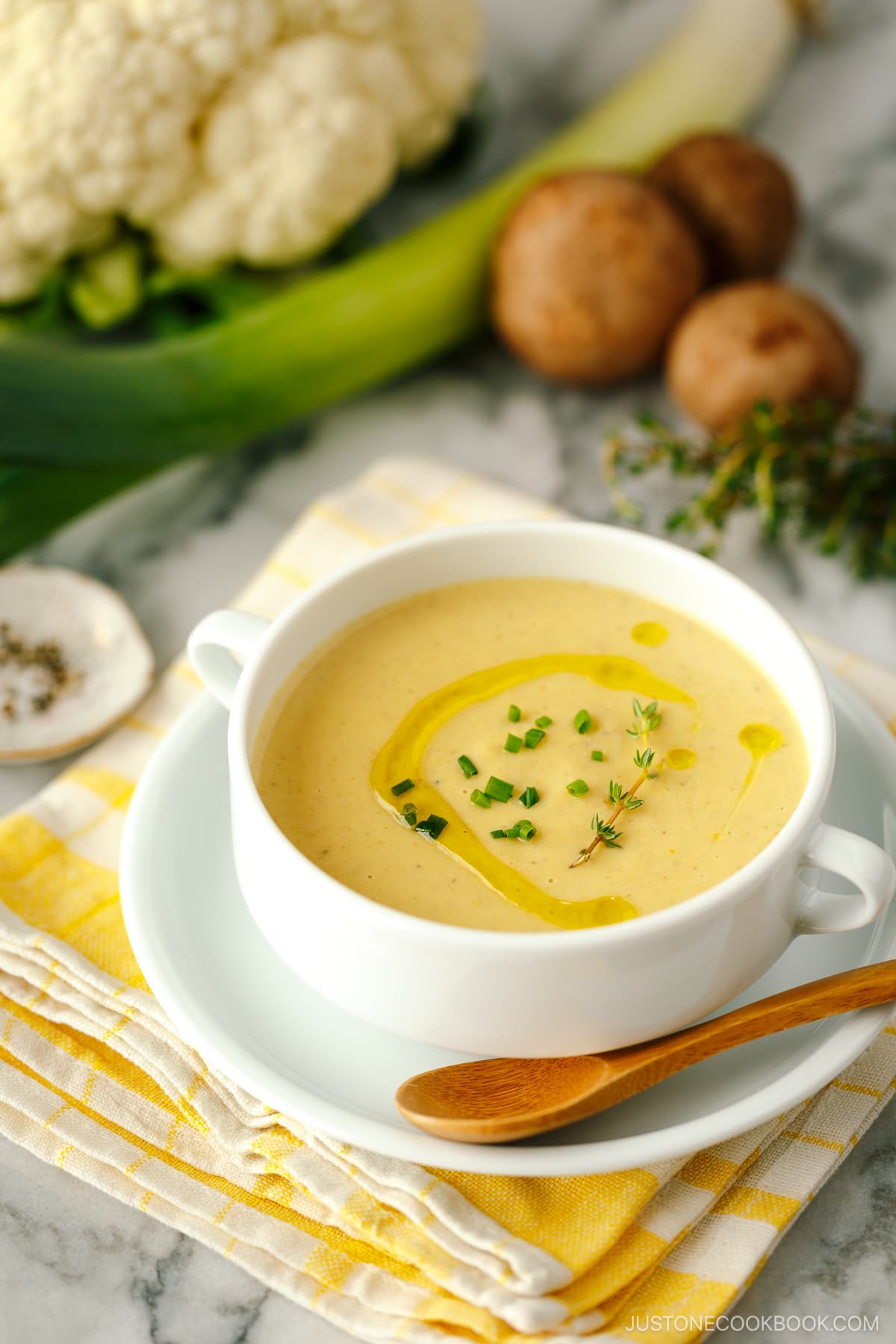 A white soup bowl containing Creamy Roasted Cauliflower Soup.