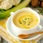 A white soup bowl containing Creamy Roasted Cauliflower Soup.