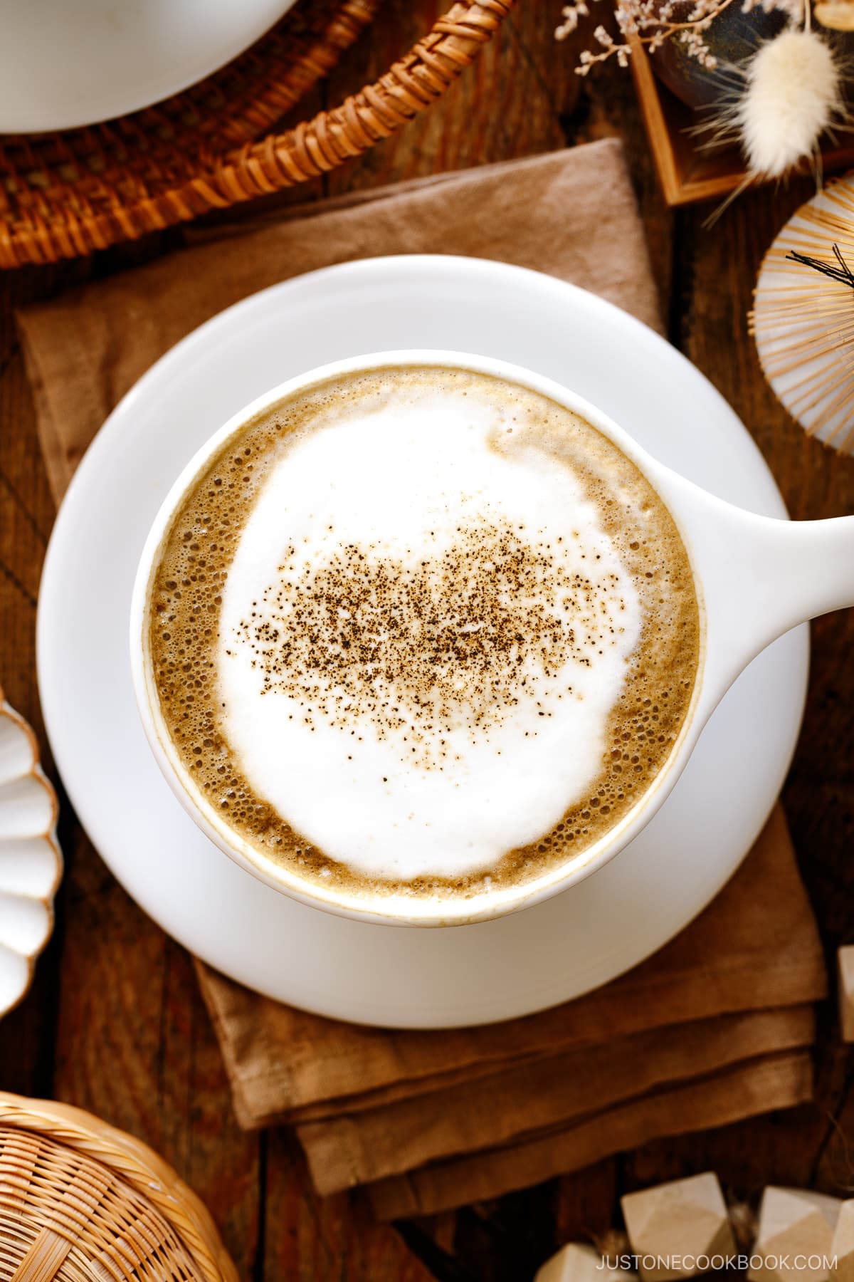 White cups containing Hojicha Latte topped with roasted green tea powder.