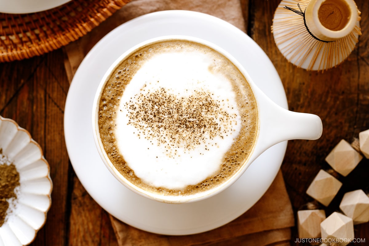 White cups containing Hojicha Latte topped with roasted green tea powder.