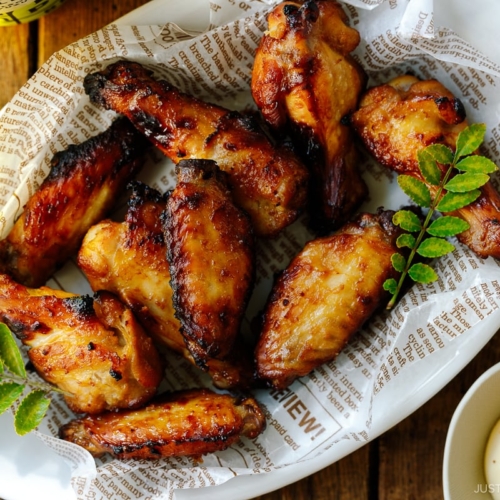 An oval ceramic white plate containing Garlic Miso Chicken Wings.