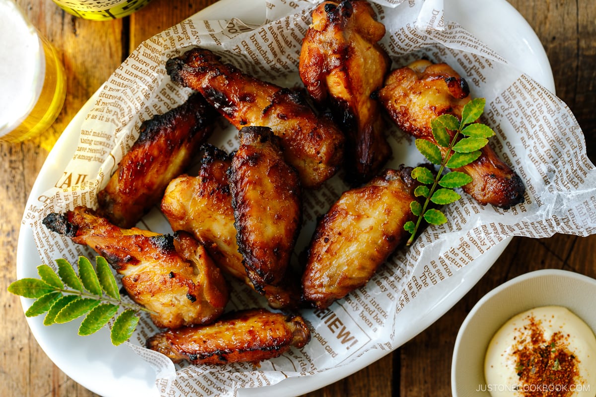 An oval ceramic white plate containing Garlic Miso Chicken Wings.