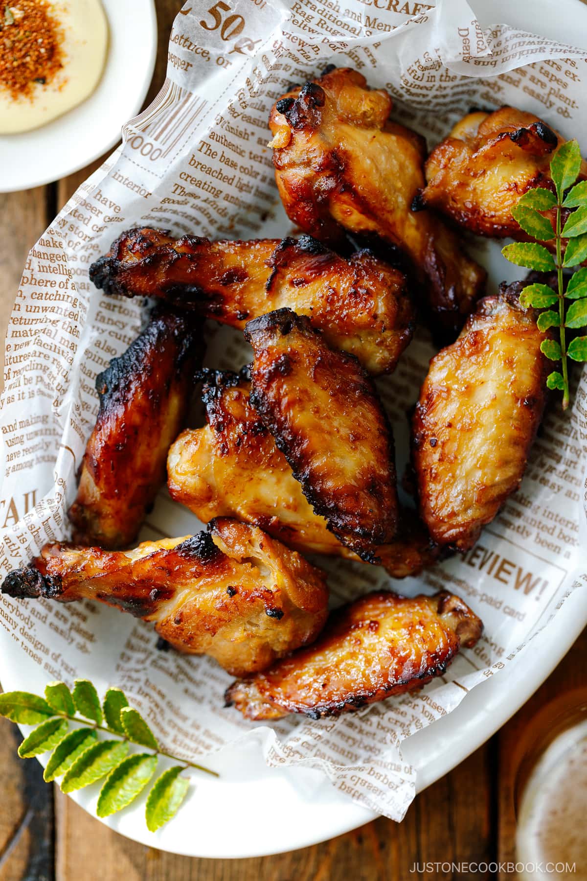 An oval ceramic white plate containing Garlic Miso Chicken Wings.