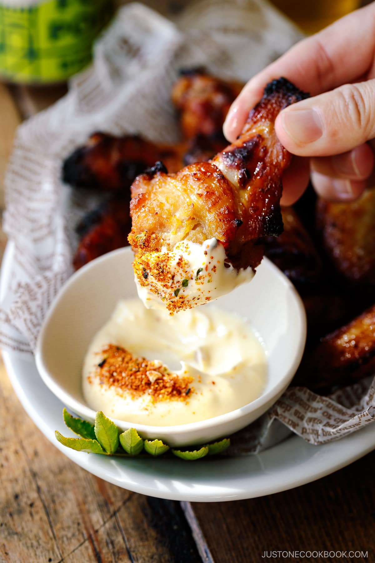 Garlic Miso Chicken Wings being dipped in Japanese mayo seasoned with shichimi togarashi.