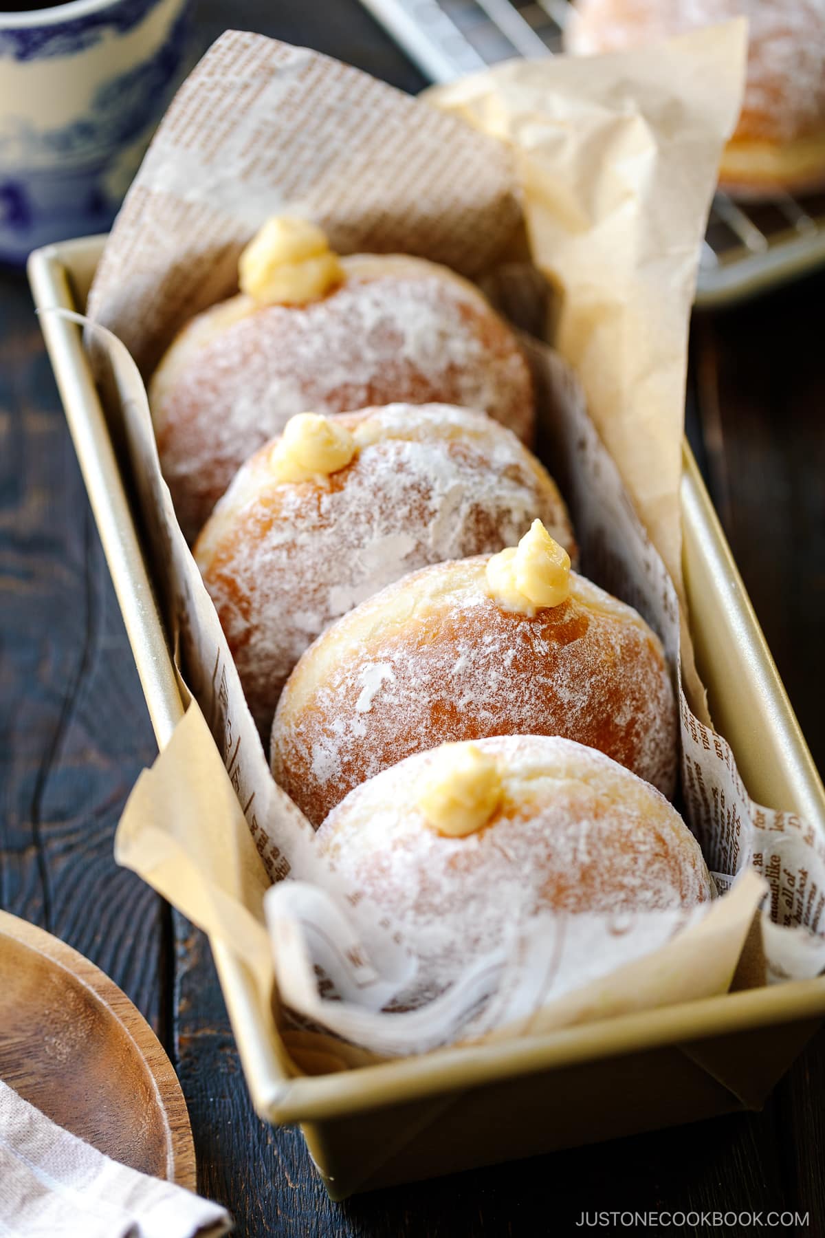 A baking pan containing Nama Donuts, dusted with powdered sugar and filled with the custard.