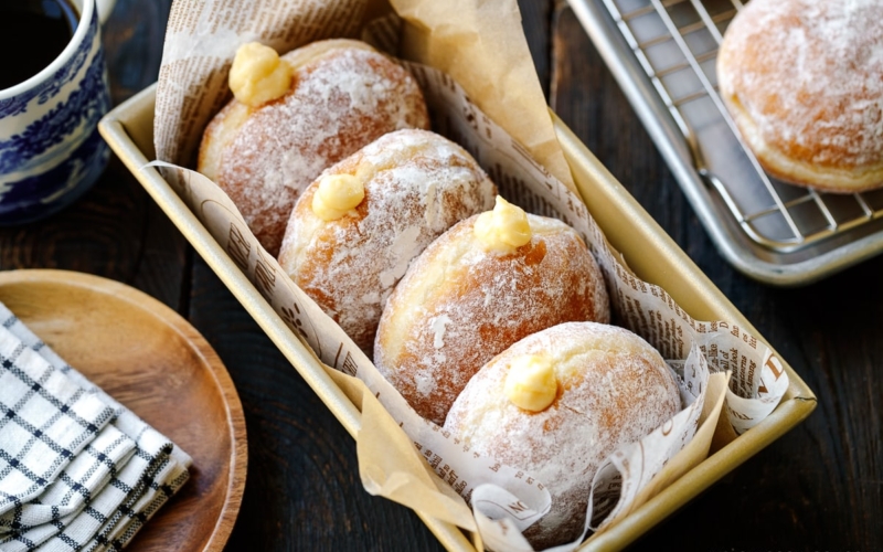 A baking pan containing Nama Donuts, dusted with powdered sugar and filled with the custard.
