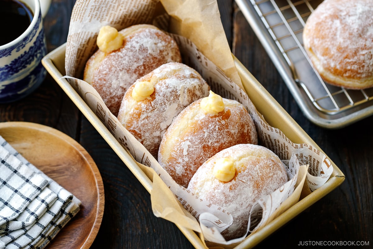 A baking pan containing Nama Donuts, dusted with powdered sugar and filled with the custard.