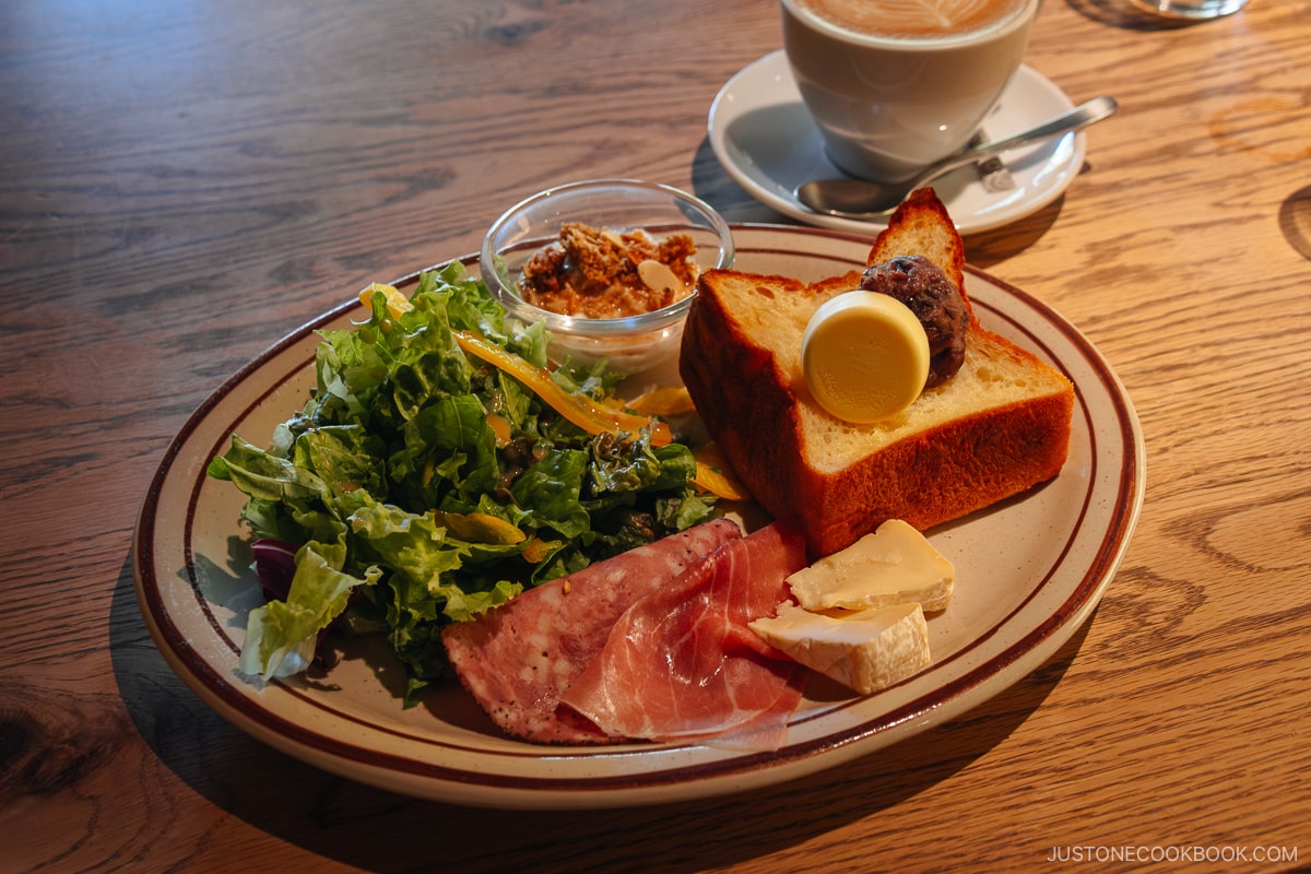 Breakfast plate with salad, cured meat, cheese and toast with red bean paste and butter
