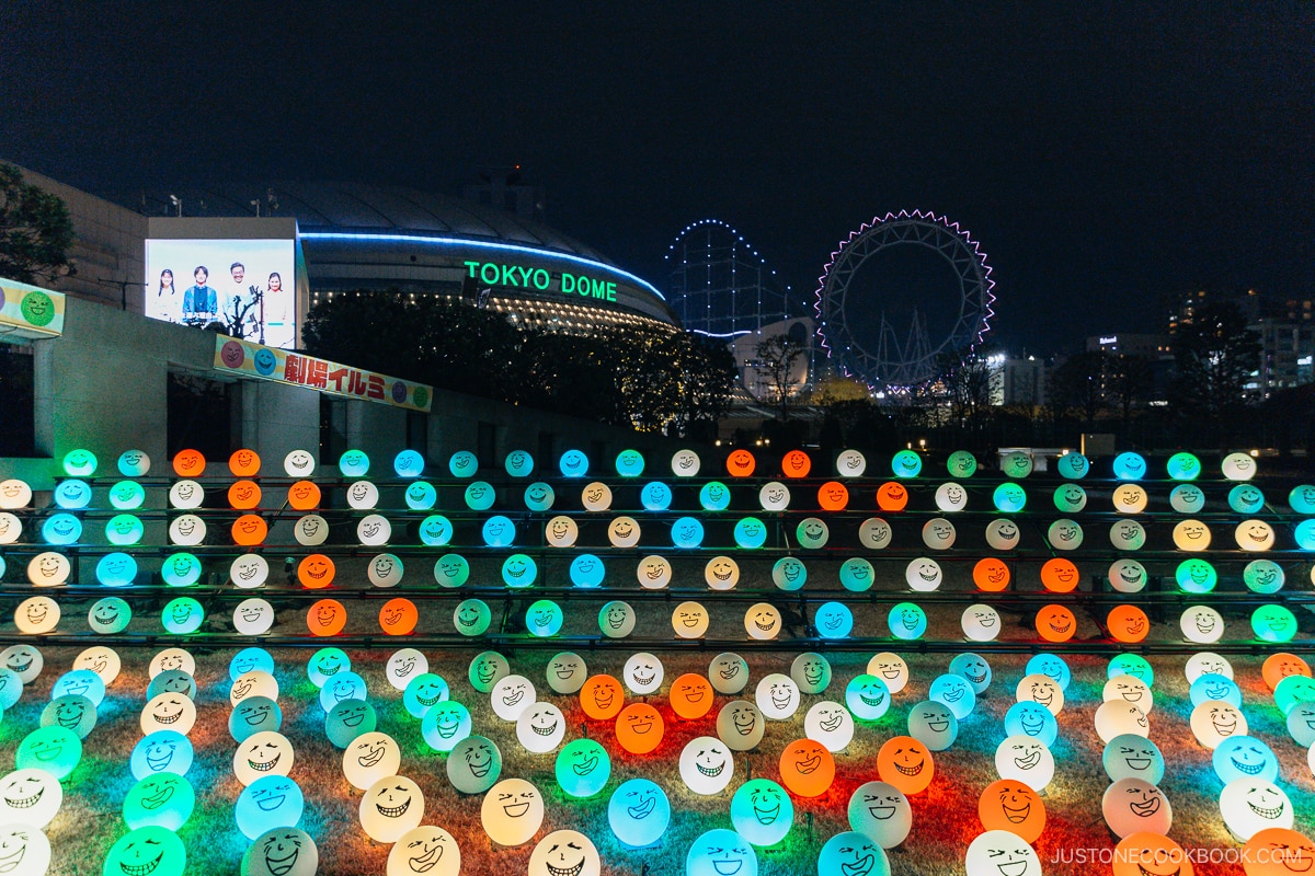 Illuminated balls with drawn laughing faces on them and Tokyo Dome in the background