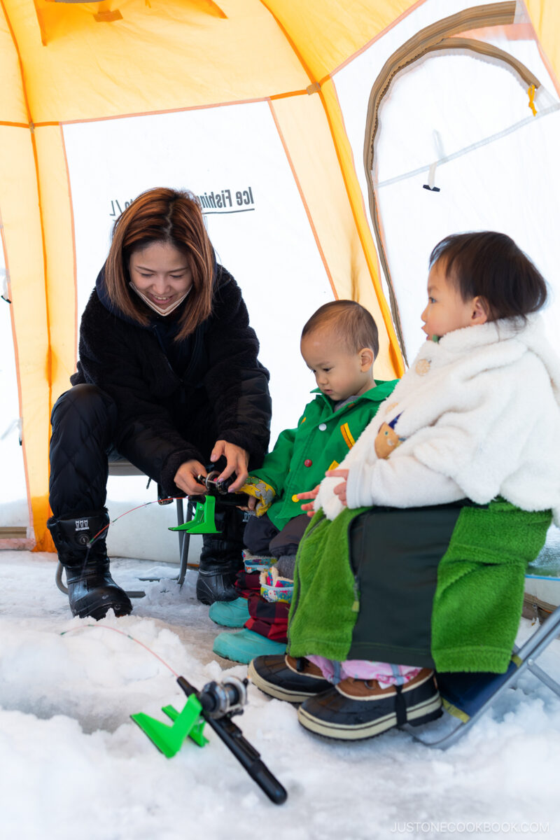 Family ice fishing in a tent on a frozen lake