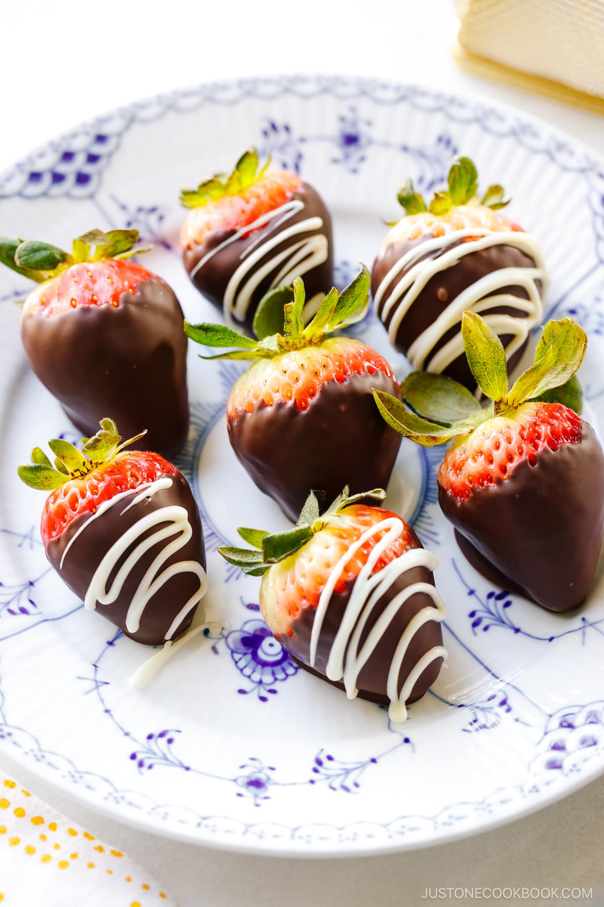 Seven homemade chocolate covered strawberries on a Royal Copenhagen plate.