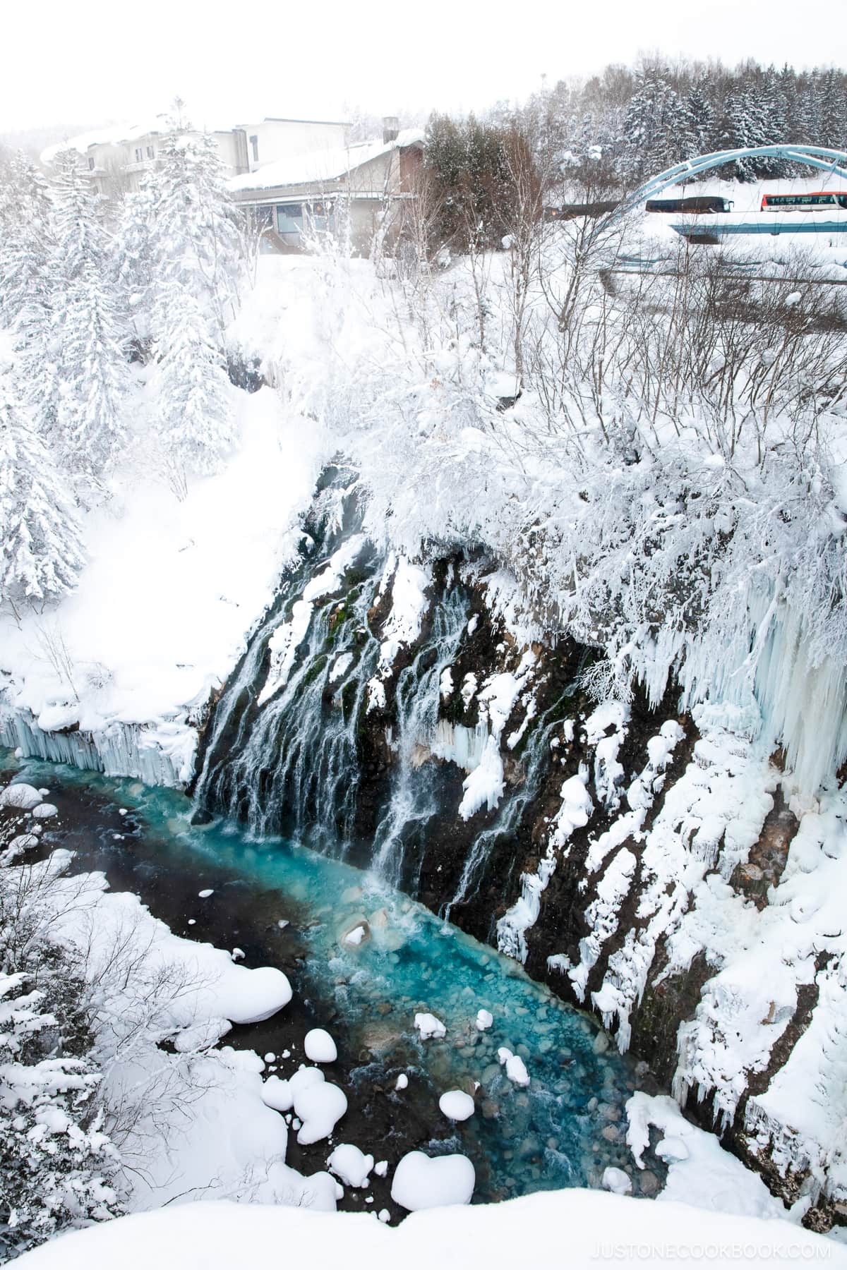 Frozen waterfall covered in snow and a blue river at the bottom