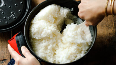 Perfectly cooked Japanese short-grain rice being fluffed with a rice paddle.