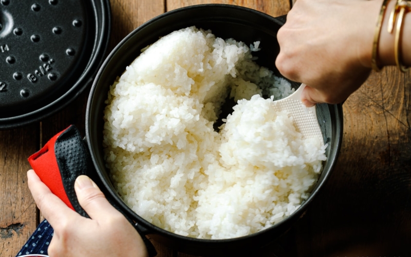 Perfectly cooked Japanese short-grain rice being fluffed with a rice paddle.