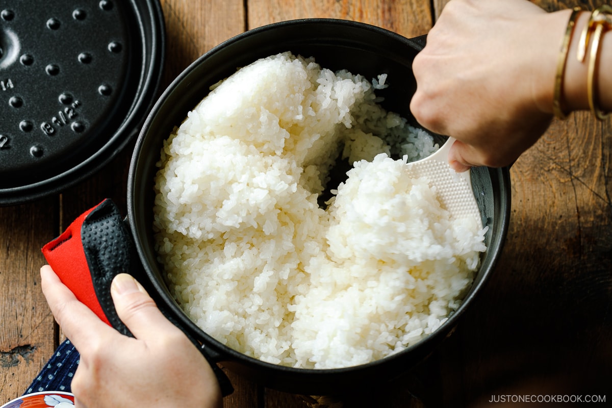 Perfectly cooked Japanese short-grain rice being fluffed with a rice paddle.