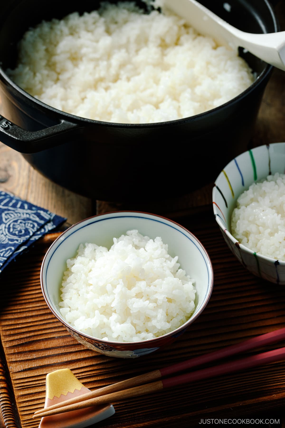 A black Staub and Japanese rice bowls containing perfectly cooked Japanese short-grain rice.