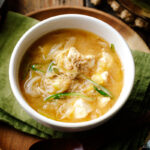 A white ceramic bowl containing Miso Soup with enoki mushrooms, tofu, and Japanese long green onion, topped with ground sesame seeds.