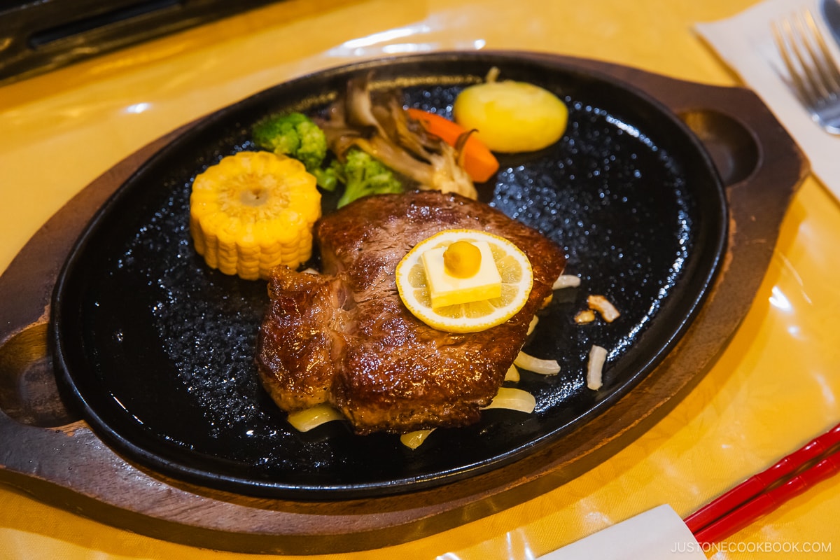 Steak on a cast iron plate and vegetables