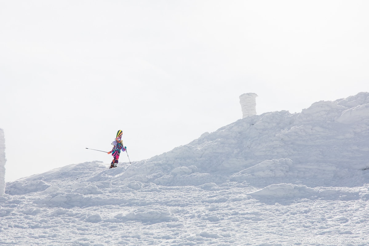 Person dressed in colorful ski gear hiking up the snow