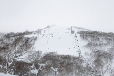 People skiing and snowboarding from the top of Mt Niseko-Annupuri