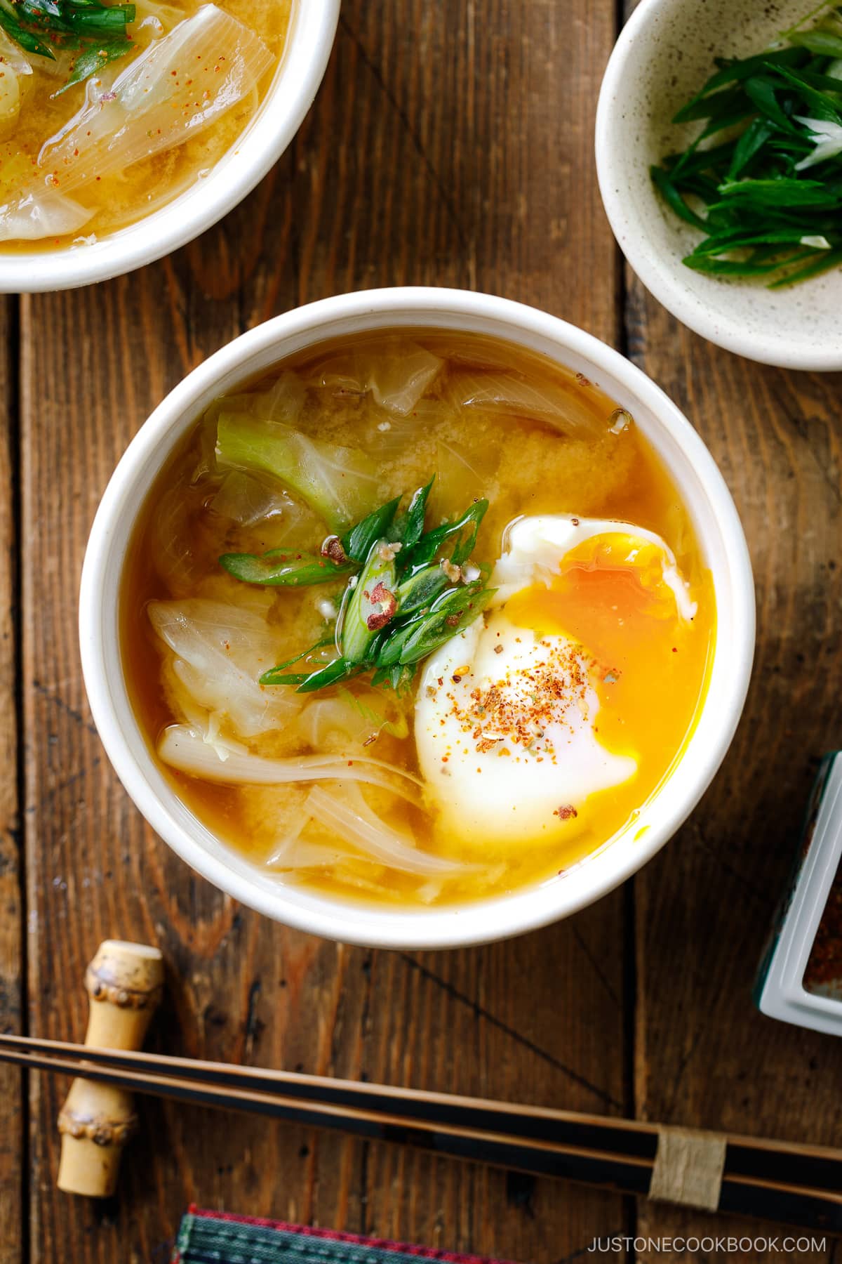 White ceramic bowls containing Cabbage and Onsen Tamago Miso Soup topped with green onions and shichimi togarashi.