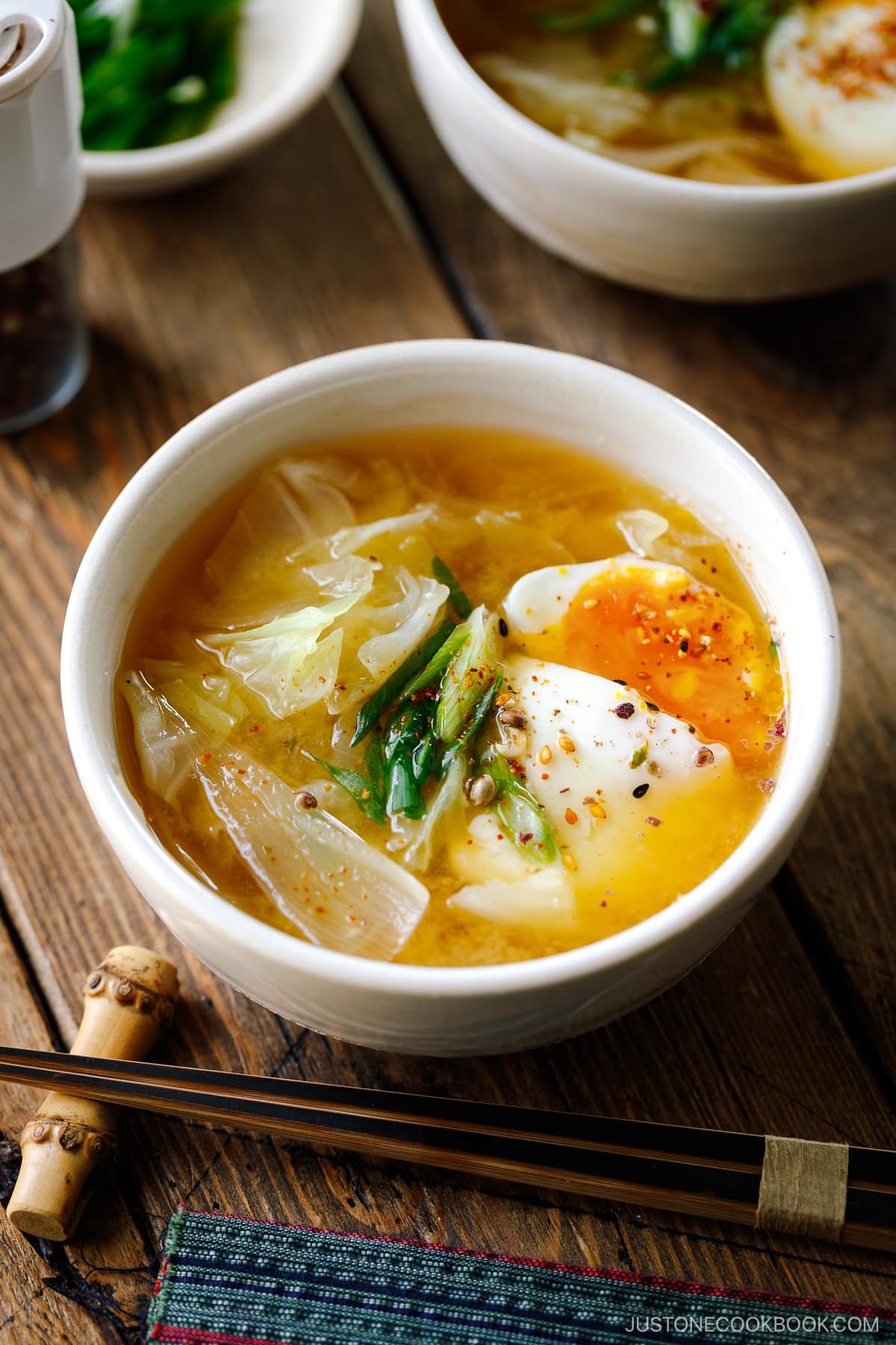 White ceramic bowls containing Cabbage and Onsen Tamago Miso Soup topped with green onions and shichimi togarashi.