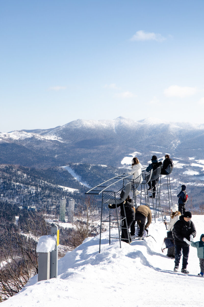 People sitting on high chairs overlooking Tomamu Ski resort and Hoshino Resort hotels