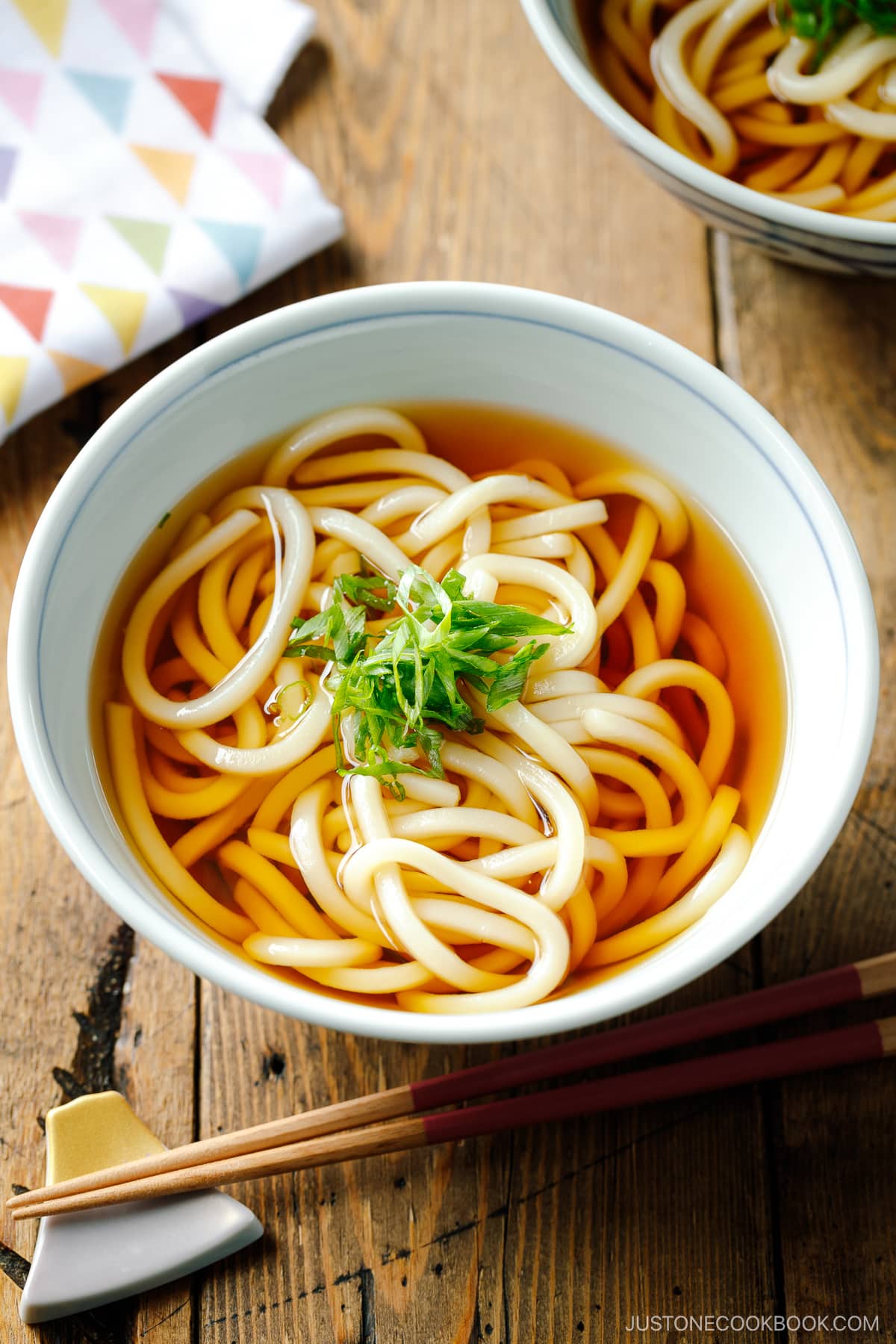 Japanese bowls containing Classic Udon Noodle Soup called Kake Udon or Su Udon, topped with sliced green onion.