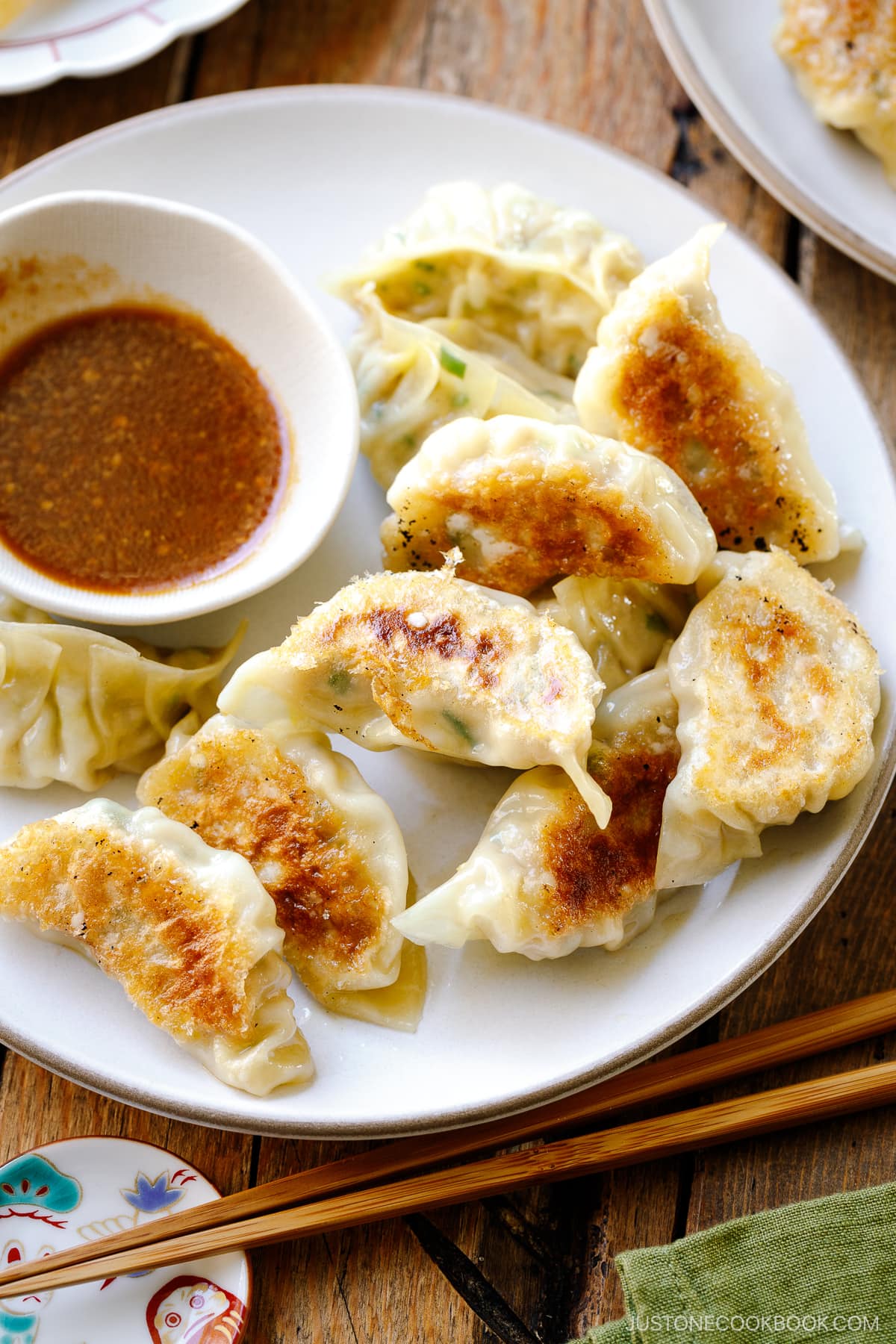 A round plate containing Japanese pan-fried dumplings, Napa Cabbage Gyoza, served with a savory miso dumpling sauce.