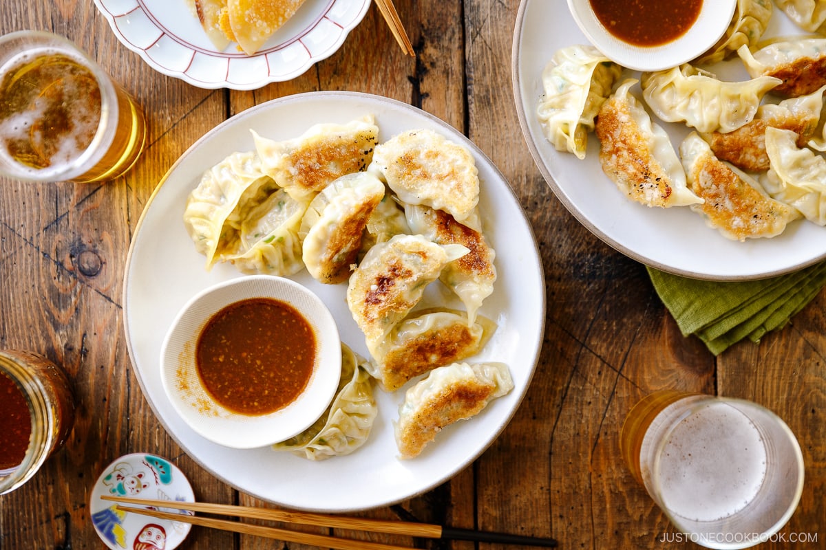 A round plate containing Japanese pan-fried dumplings, Napa Cabbage Gyoza, served with a savory miso dumpling sauce.