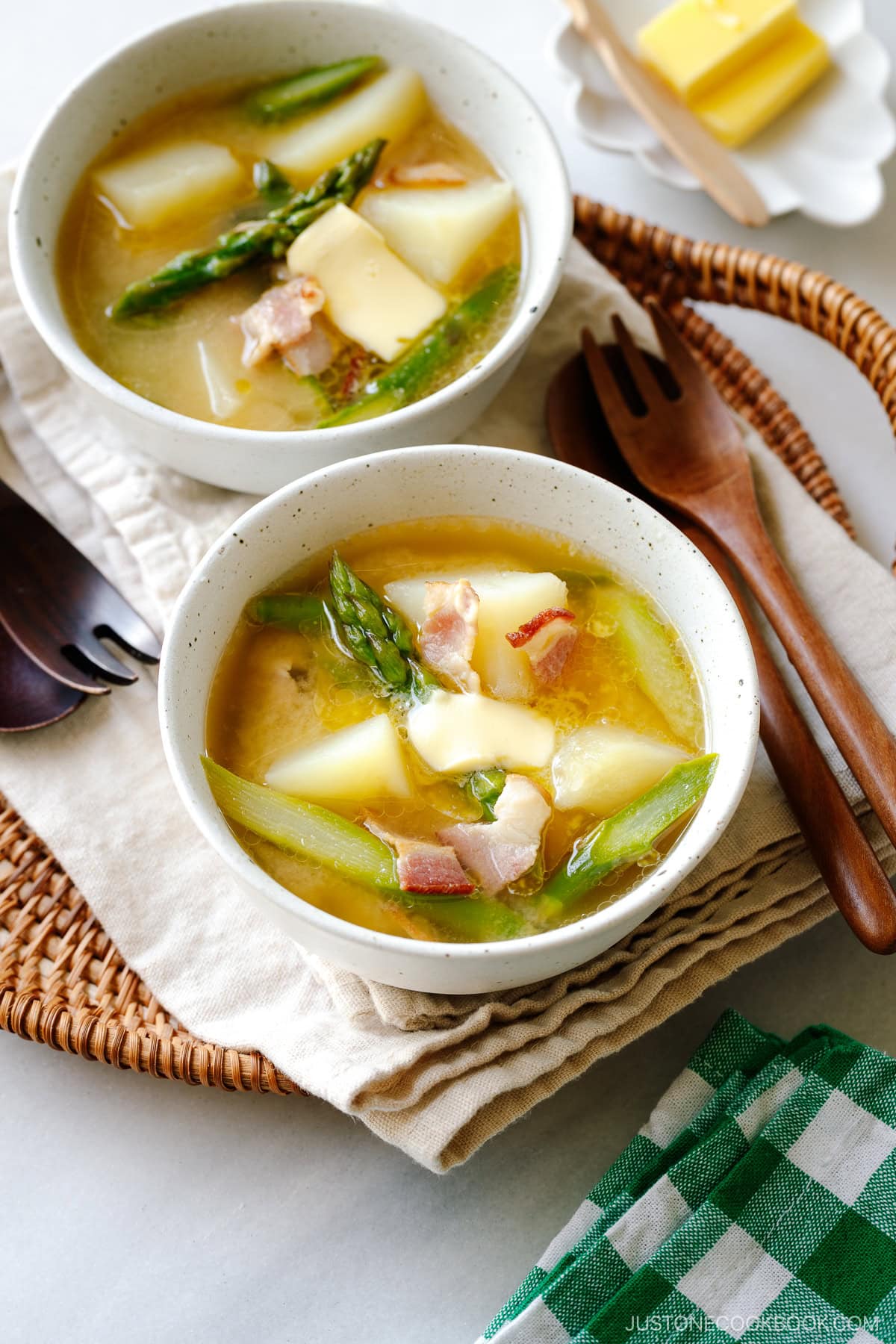 White ceramic bowls containing Bacon Asparagus Miso Soup topped with a slice of butter.