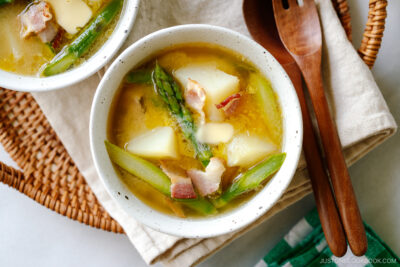 White ceramic bowls containing Bacon Asparagus Miso Soup topped with a slice of butter.
