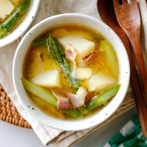 White ceramic bowls containing Bacon Asparagus Miso Soup topped with a slice of butter.