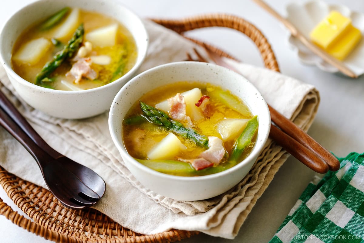 White ceramic bowls containing Bacon Asparagus Miso Soup topped with a slice of butter.