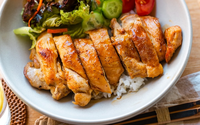 A bowl containing Chicken Teriyaki glazed with homemade teriyaki sauce on the bed of steamed rice.