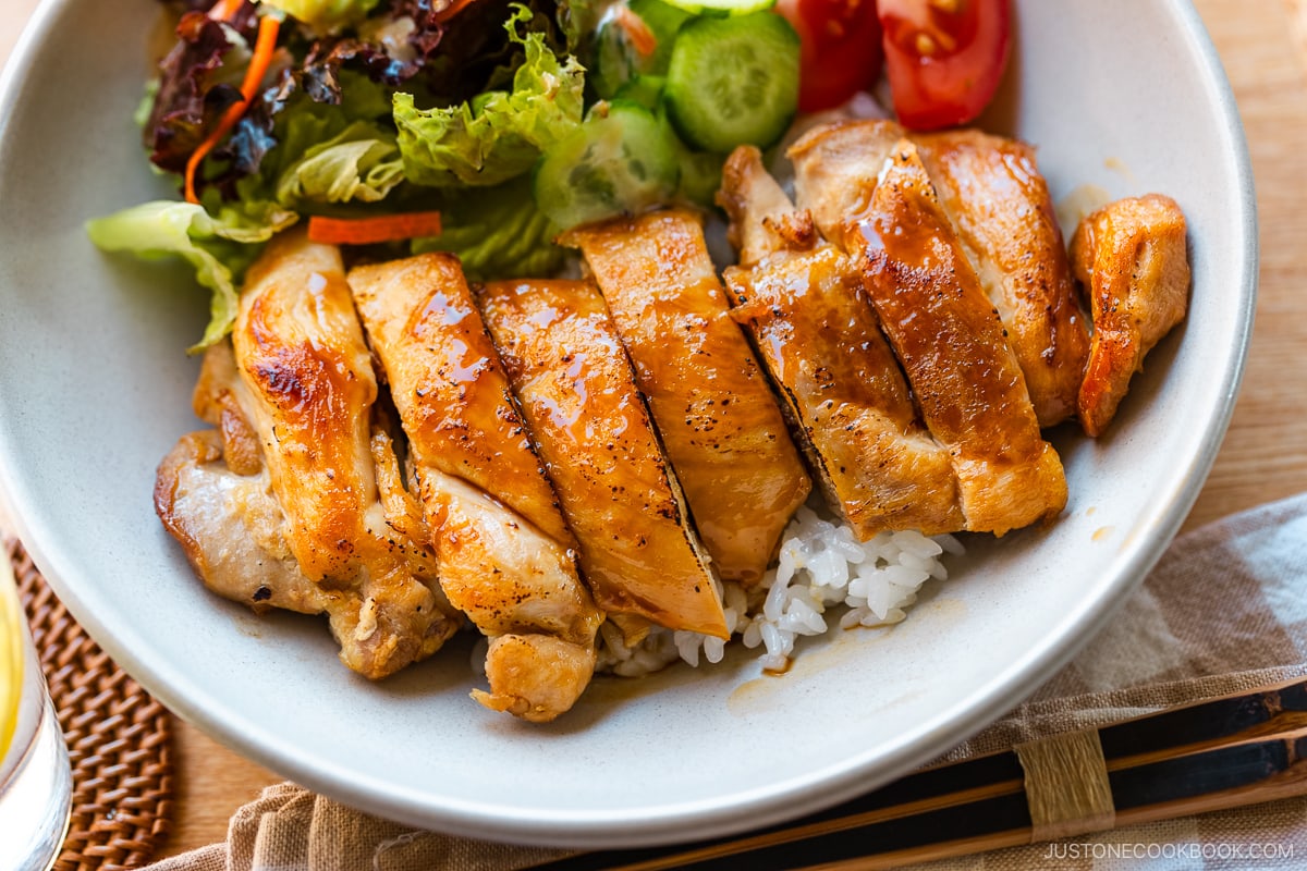 A bowl containing Chicken Teriyaki glazed with homemade teriyaki sauce on the bed of steamed rice.