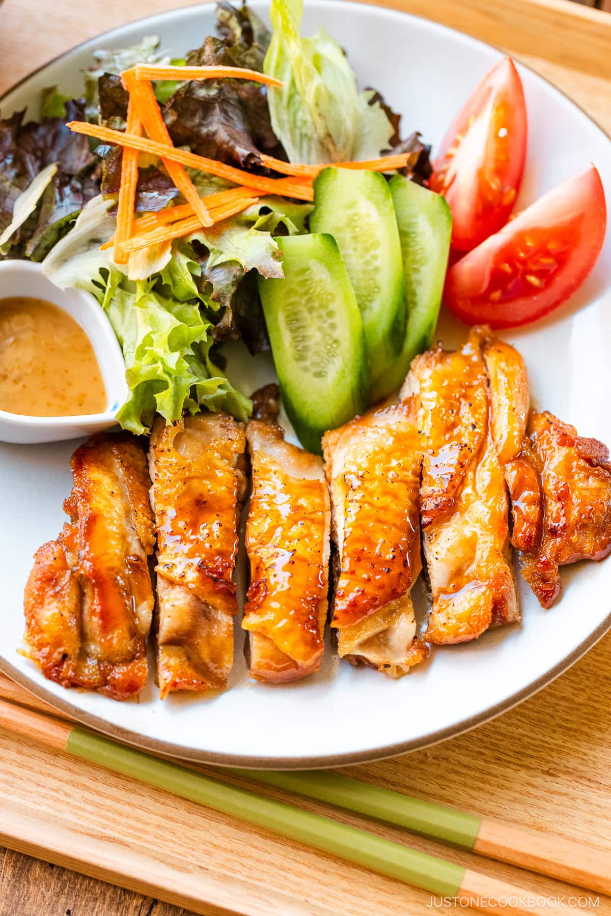 A round plate containing Chicken Teriyaki glazed with homemade teriyaki sauce.