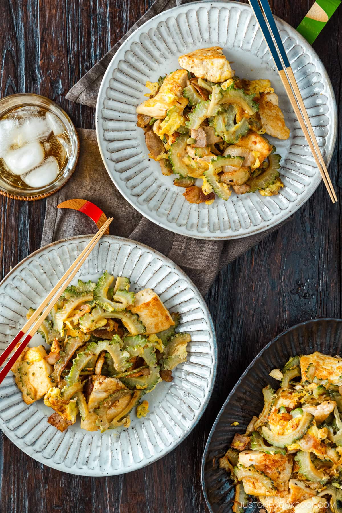 Round white plates containing Goya Champuru, a bitter melon stir-fry with tofu, egg, and pork belly.