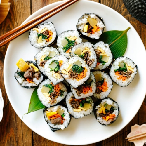 A white round plate containing sliced Kimbap (Korean Seaweed Roll).