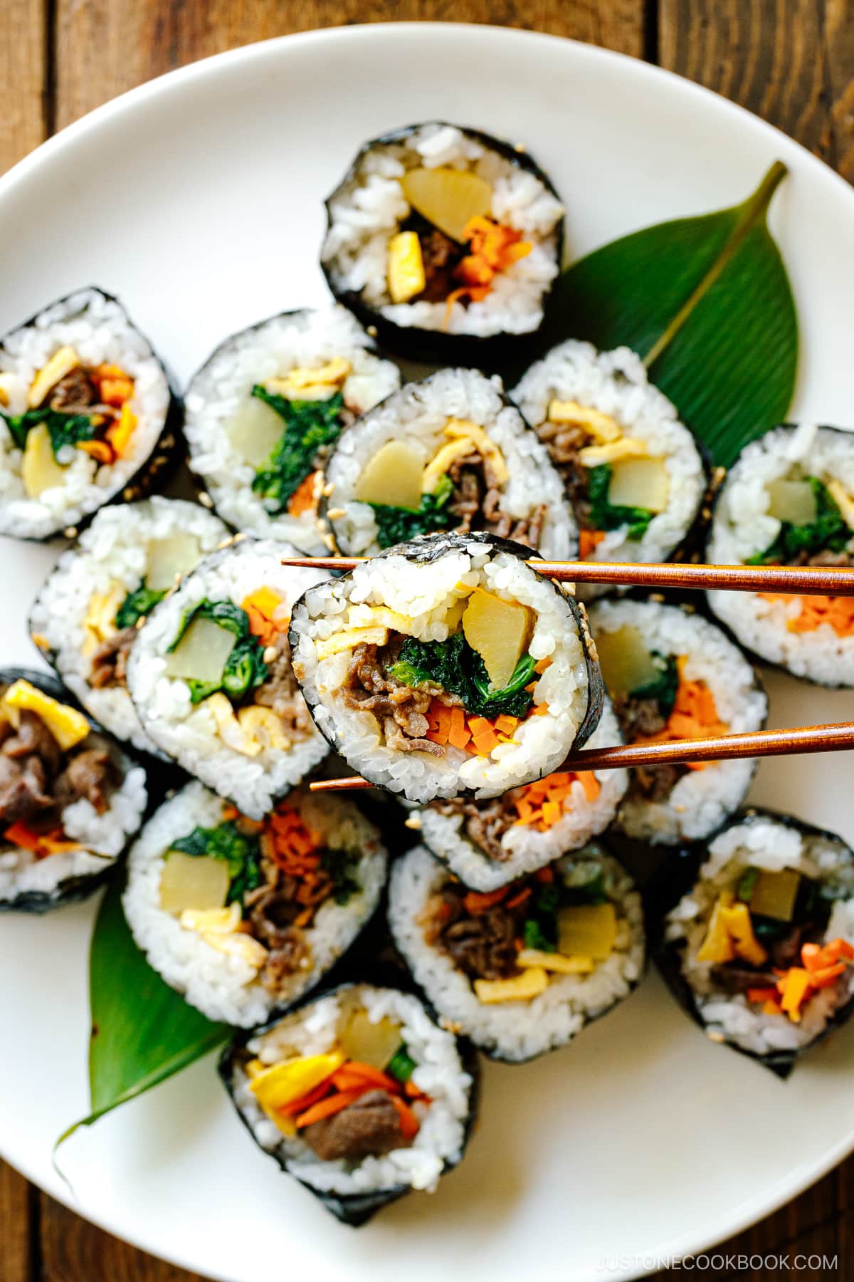 A white round plate containing sliced Kimbap (Korean Seaweed Roll).