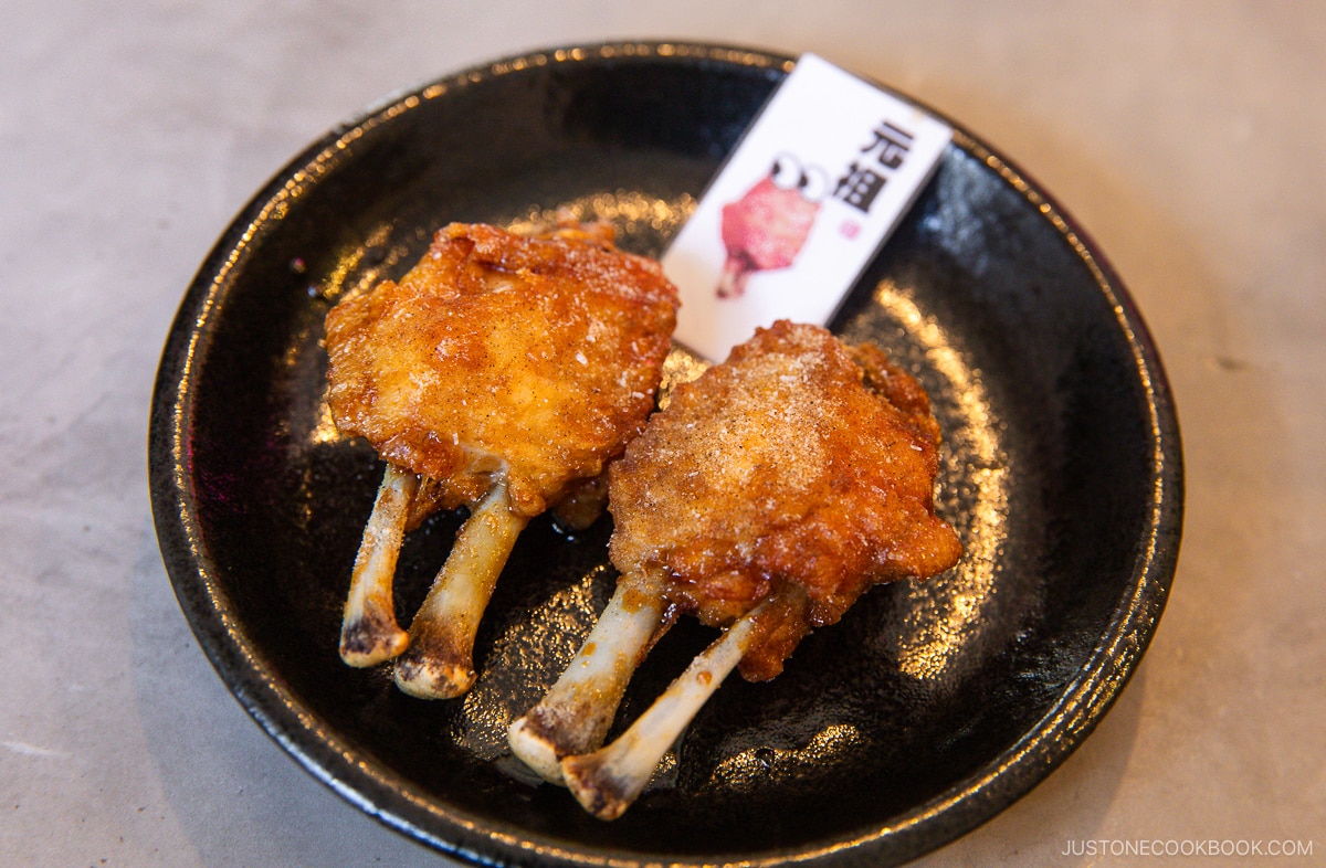 Two chicken wings on a black plate