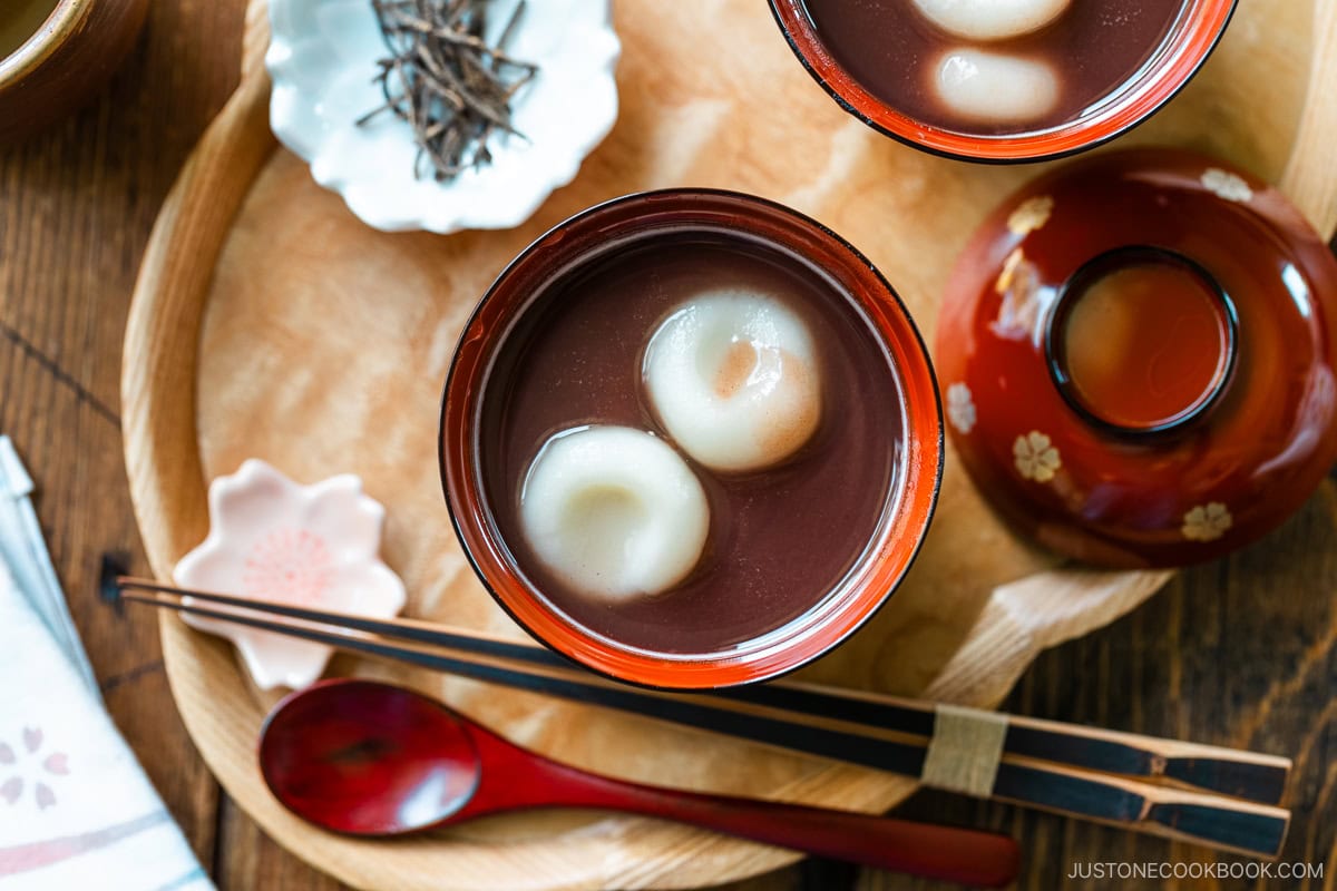 Red lacquered bowls containing red bean soup with mochi balls.