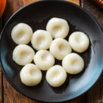 A round black plate containing shiratama dango (mochi balls).