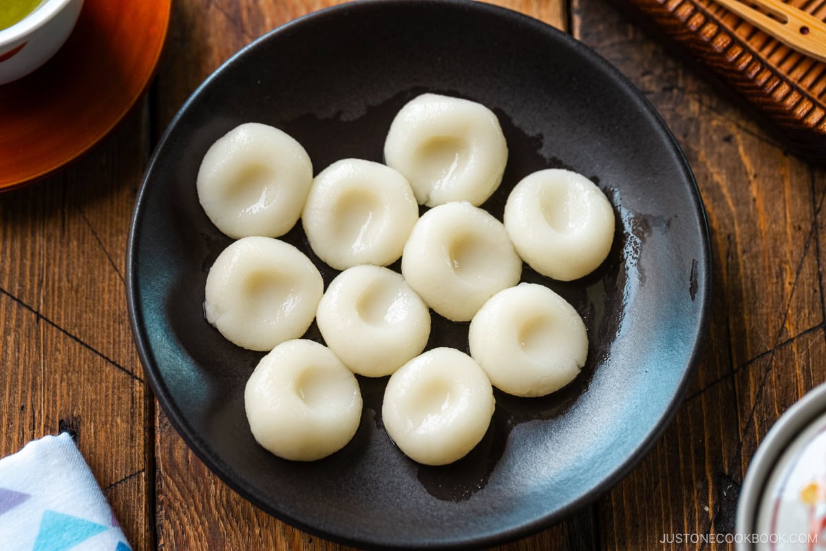 A round black plate containing shiratama dango (mochi balls).