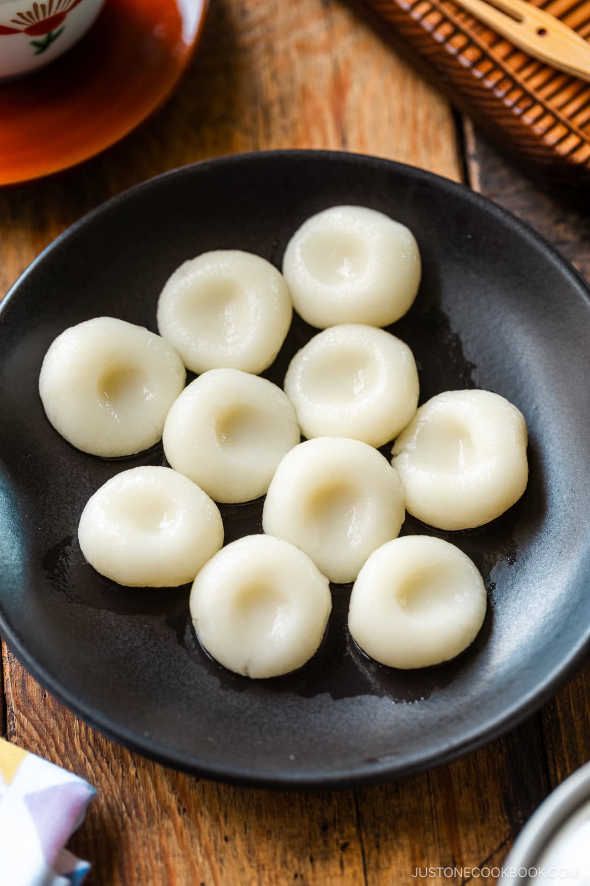 A round black plate containing shiratama dango (mochi balls).