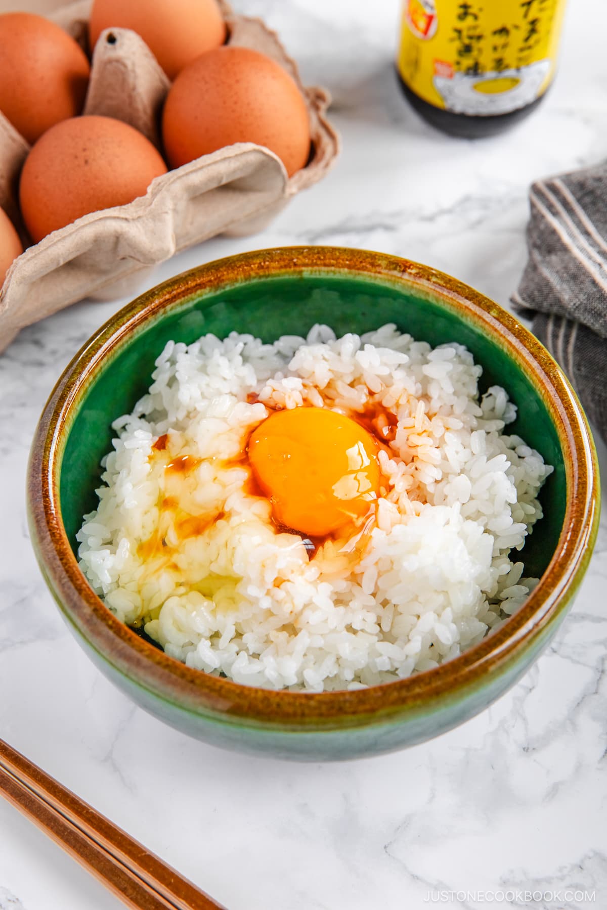 A bowl containing steamed rice, raw egg, sprinkled katsuobushi, and a drizzle of soy sauce.