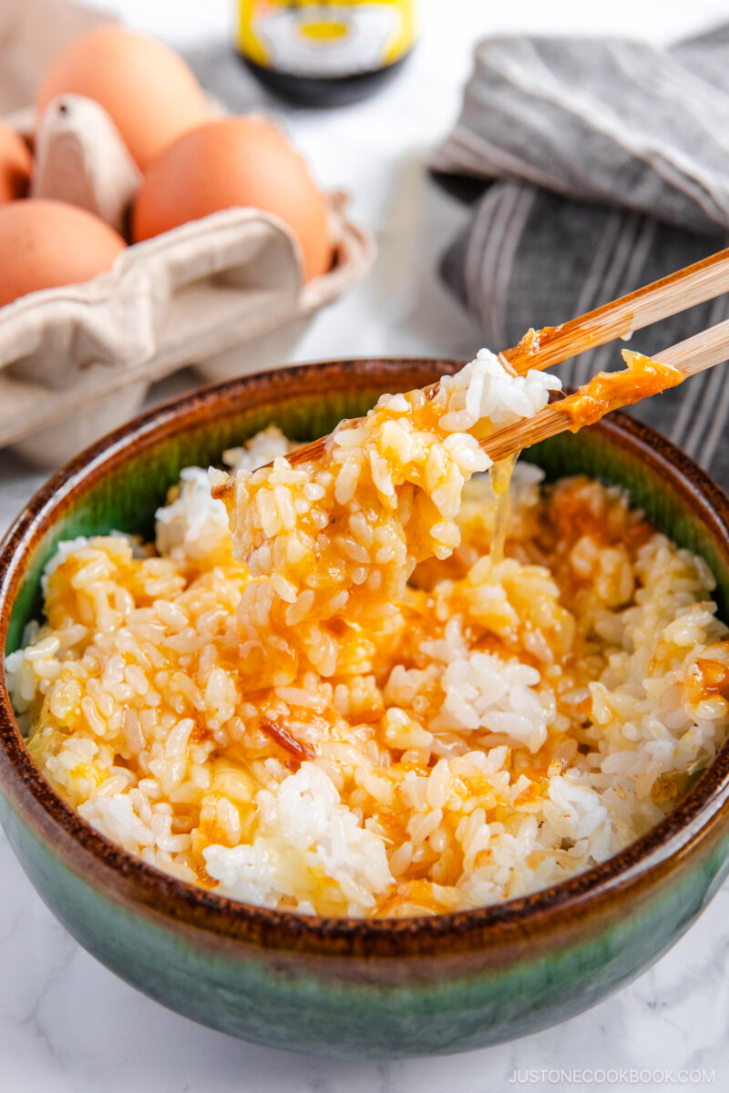 A bowl containing steamed rice, raw egg, sprinkled katsuobushi, and a drizzle of soy sauce.